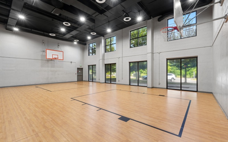 Full indoor basketball court with two basketball hoops and large windows
